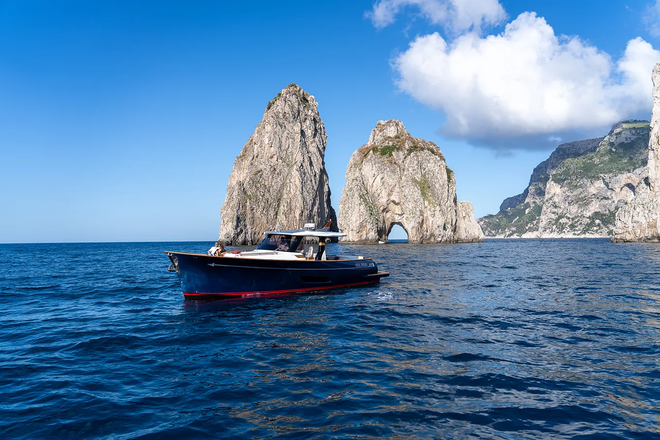 Couple at the bow with a view of the Faraglioni rocks