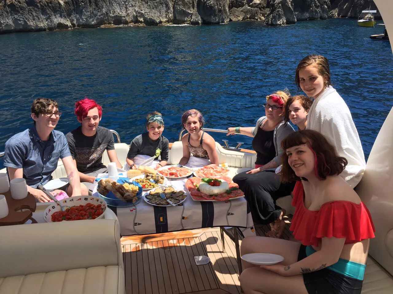 Group of friends have a lunch on board during a boat tour in Ischia